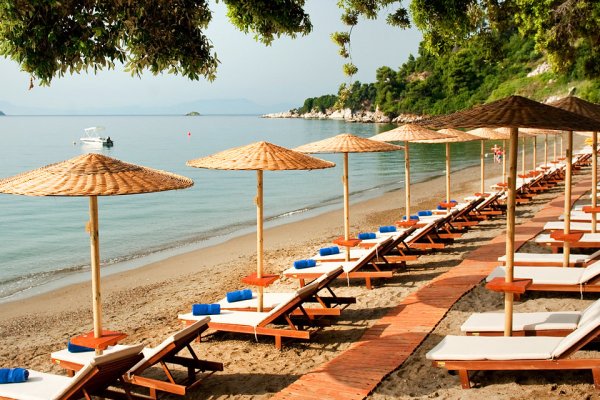 Wooden sunbeds and straw beach umbrellas lined up by the sea on Vasilias beach.