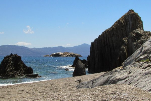 Grey rocks and boulders on the sand and in the sea at Xanemos Beach on Skiathos island.