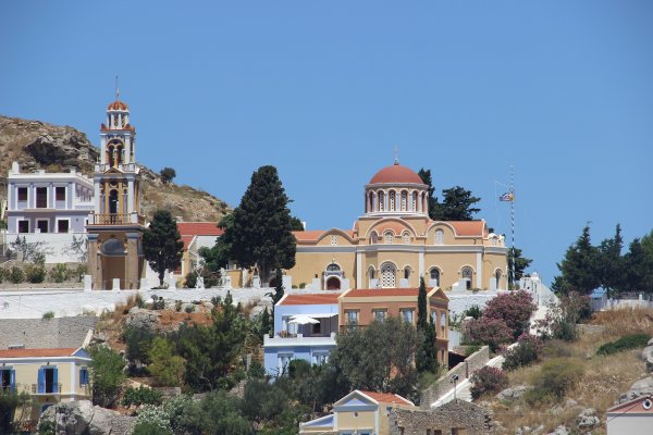 Evaggelistria church in earthy colors and its elaborate belfry against the blue sky in Symi.