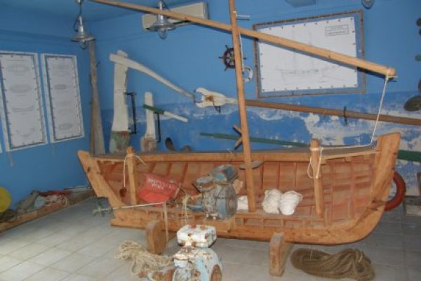 The profile view of an old fishing boat and many fishing tools with a blue wall in the background.