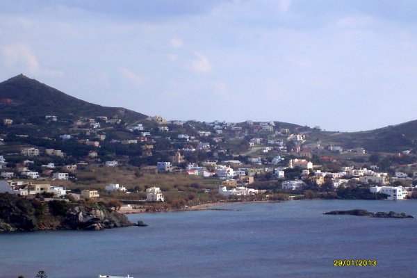A bay peppered with white houses and a barren hill sandwiched between a blue sky and a blue sea.