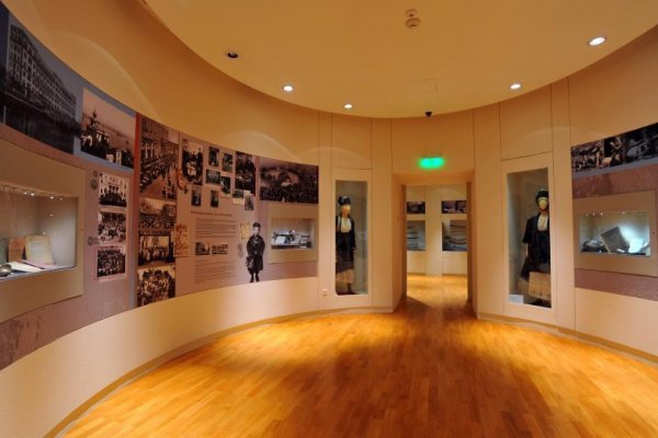 Exposés on the walls of an oval room and two traditional costumes close to the entrance.