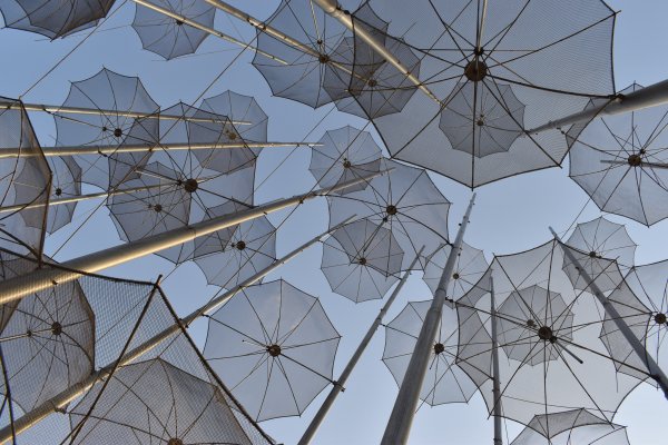 A stack of see-through umbrellas viewed from below with the sky as background.