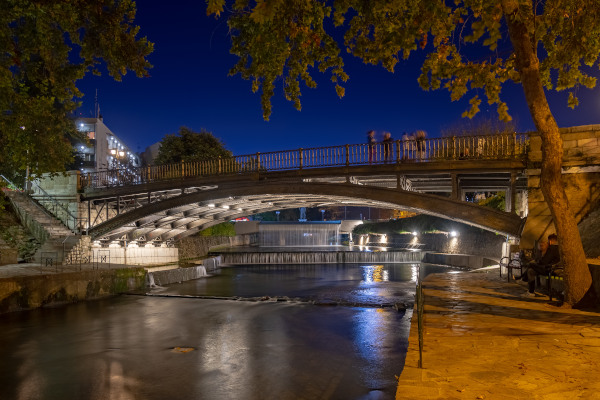 The pedestrian metal-made central bridge of Trikala, as it is illuminated during the night.
