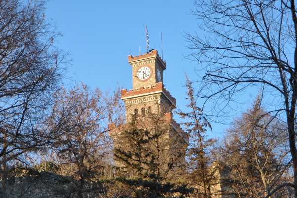 The Clock Tower of Trikala during a winter sunny day emerging through trees.