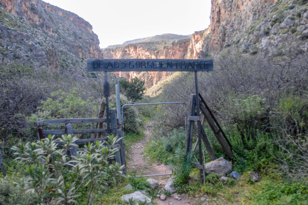 The entrance of the Zakros Gorge with a wooden sign writing «Dead's Gorge Entrance». 